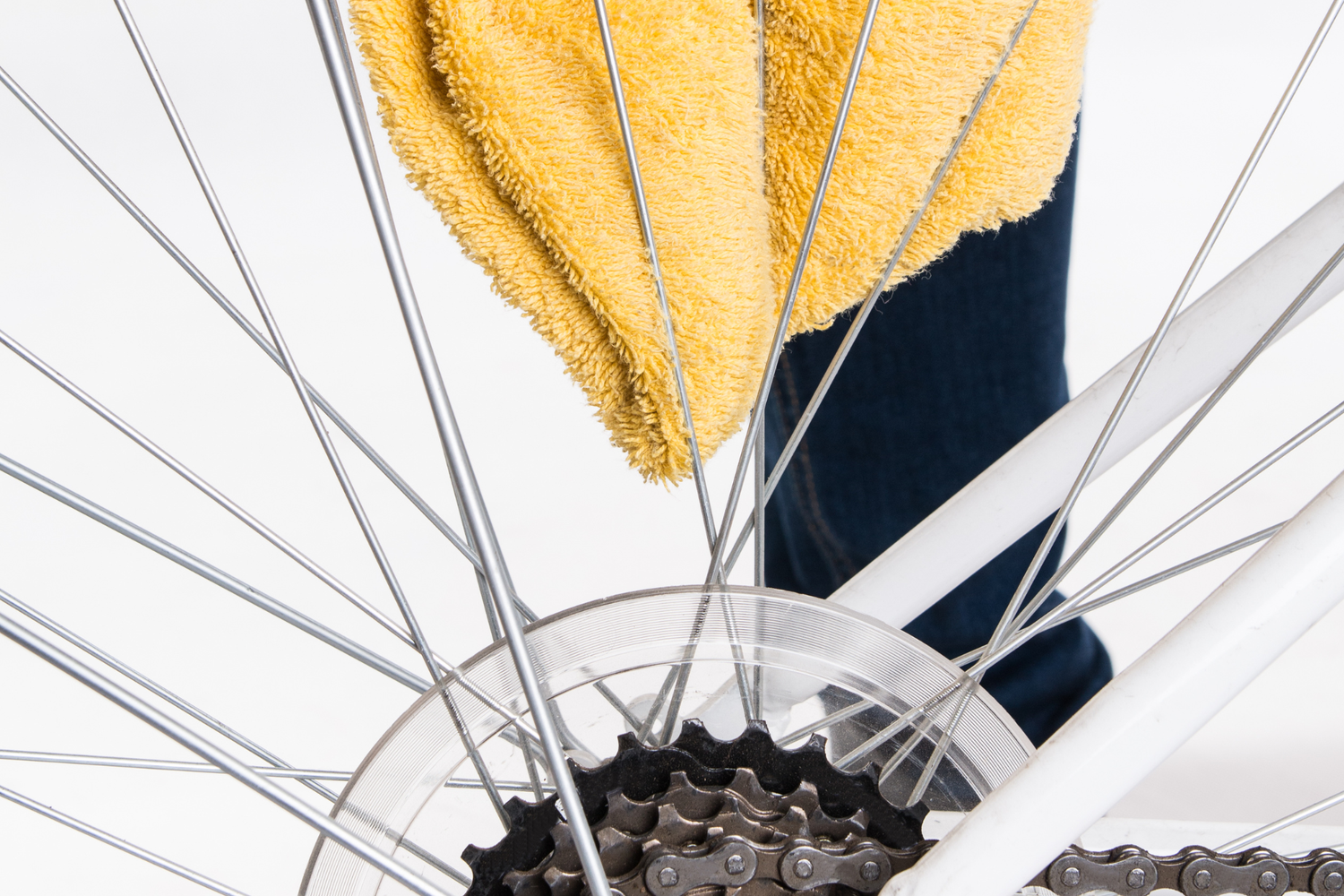 Person cleaning a bicycle chain with a yellow cloth on a white background