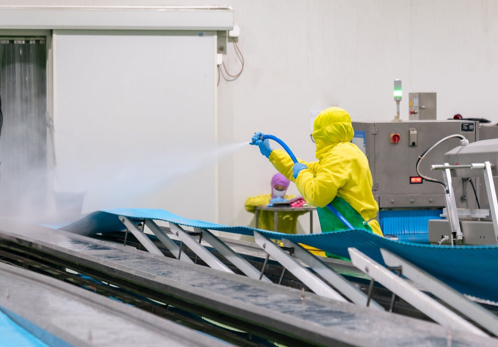 Worker use high pressure water spray cleaning conveyor belt