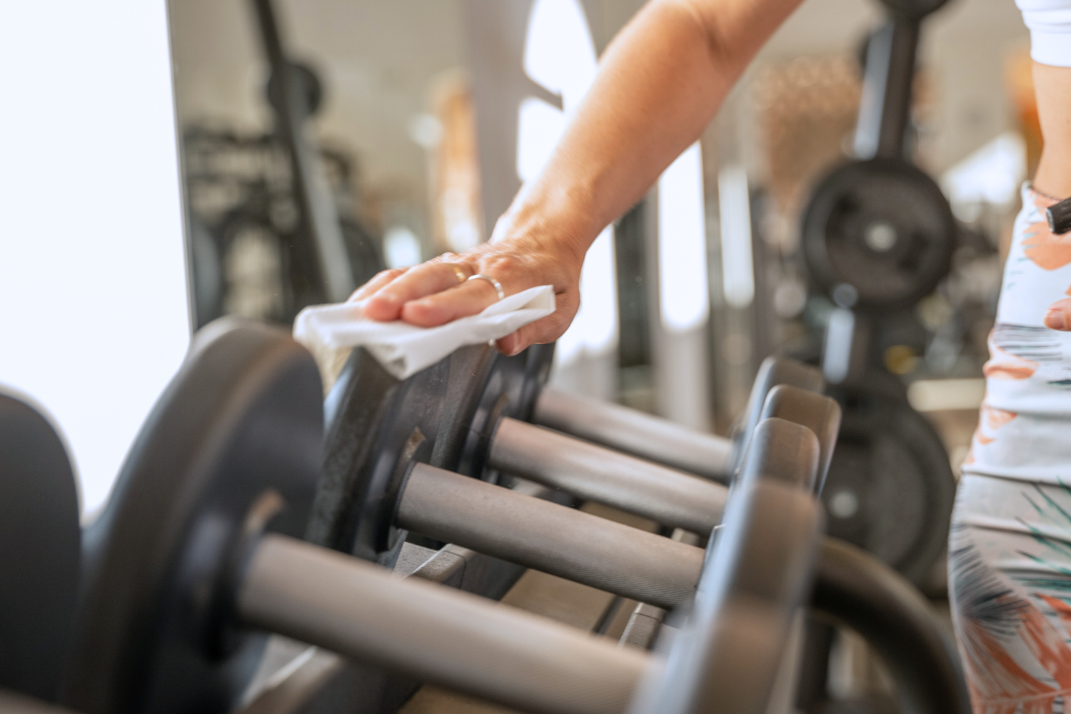 Person cleaning gym equipment with a towel