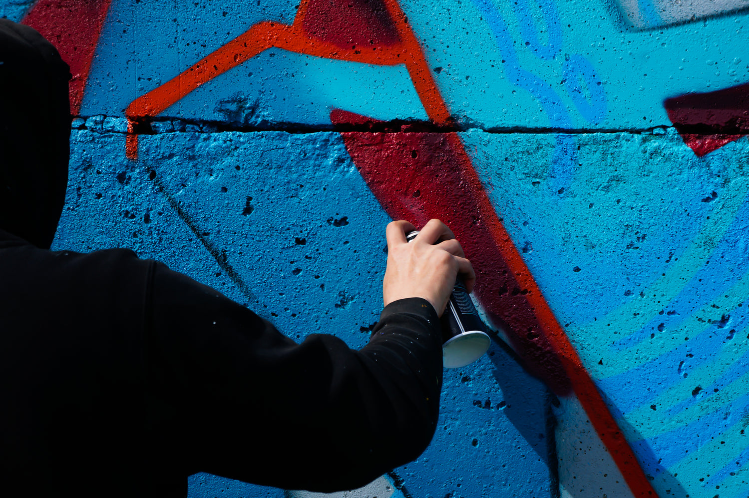 Person spray painting a colorful mural on a wall