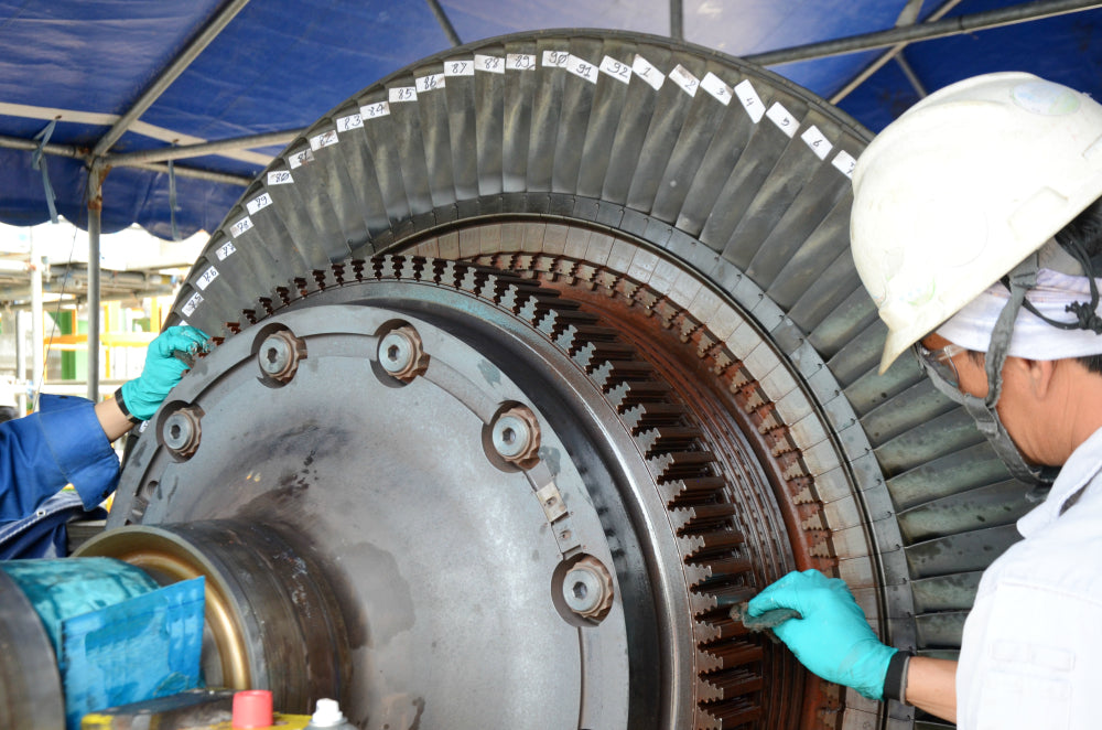 Engineer inspecting a large mechanical gear component outdoors.