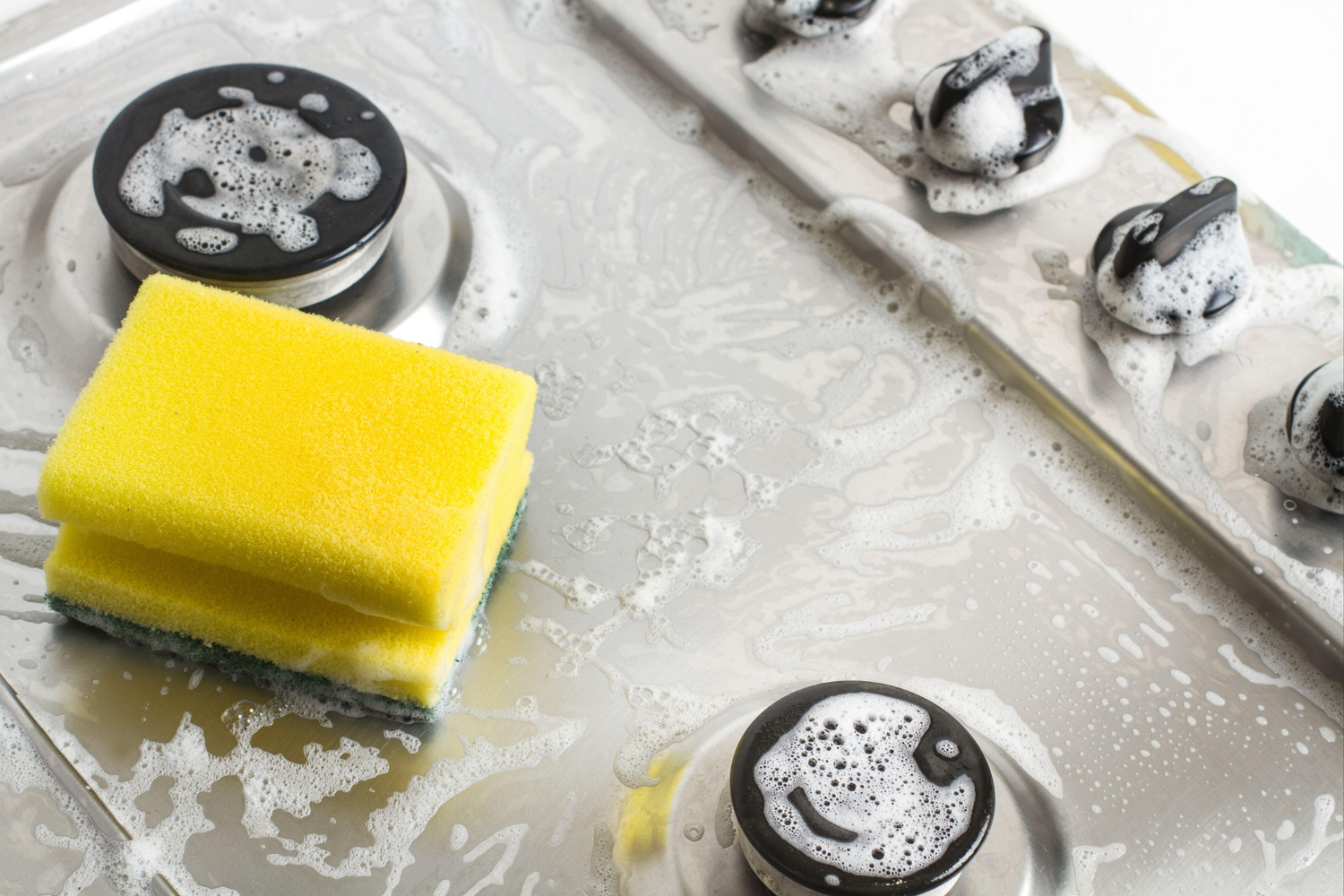 Yellow sponge on a gas stove with soapy water