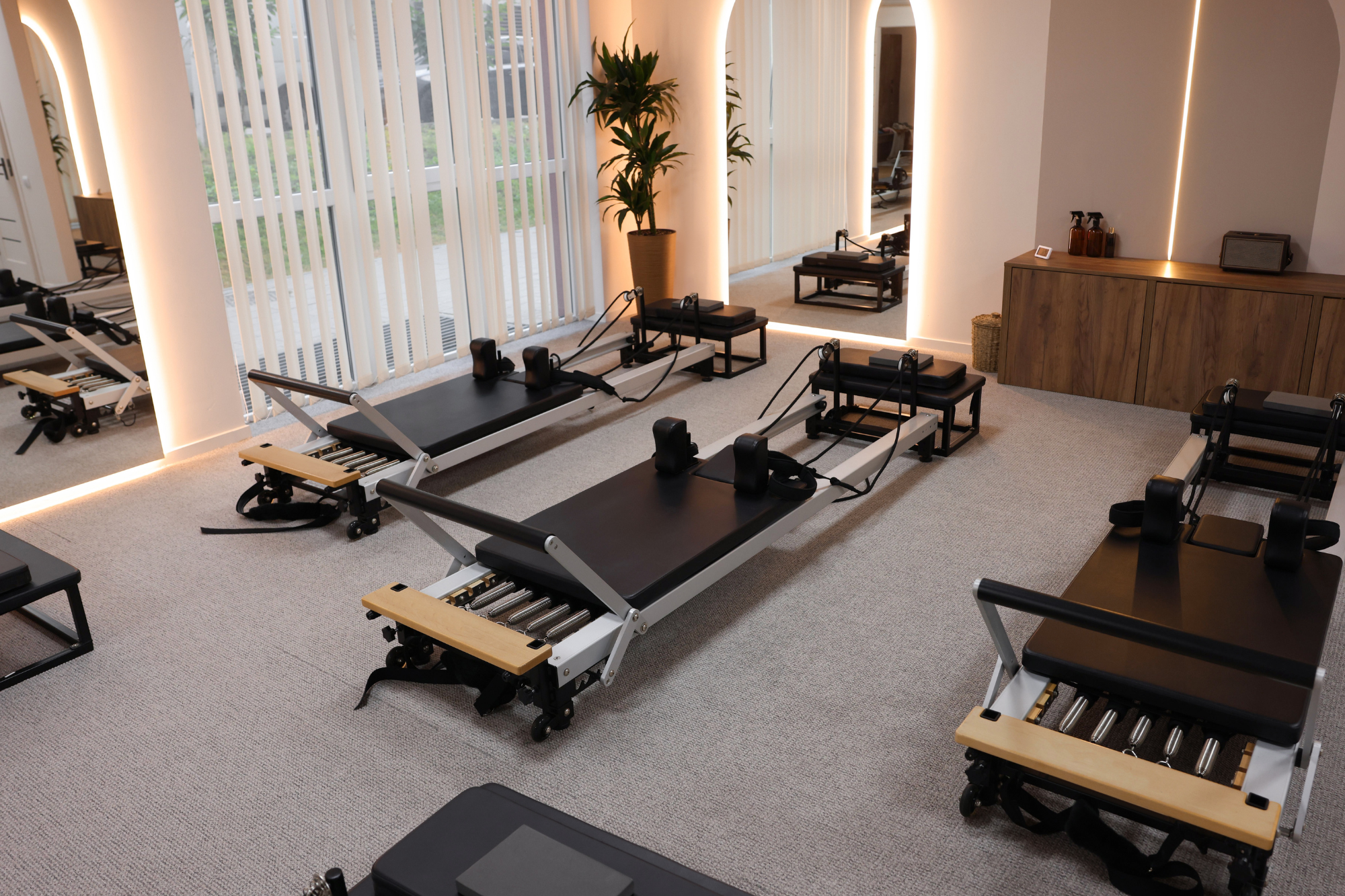 Pilates reformers in a modern fitness studio with large windows.