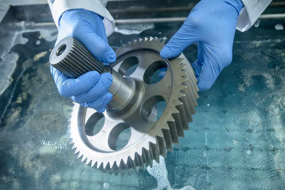 Person wearing blue gloves holding a mechanical gear
